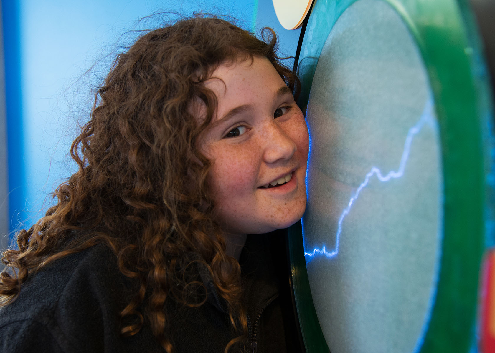 A girl puts her cheek to an electricity monitor
